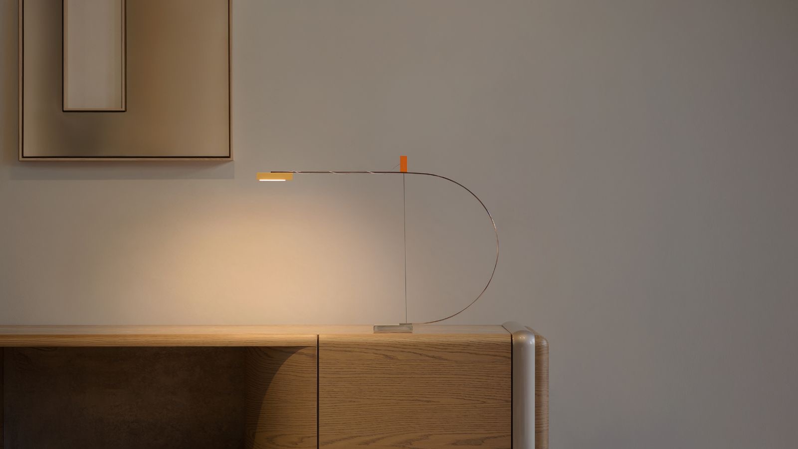 Nemo Cupido – Tischleuchte mit geschwungenem Bogen auf einem Sideboard